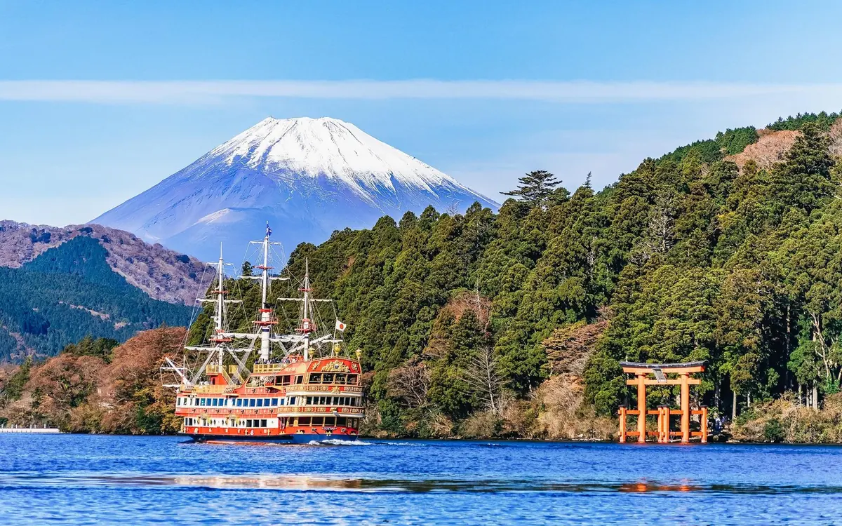 A sightseeing ship on Lake Ashi passing the red torii, with Mount Fuji behind it