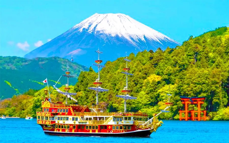 A sightseeing ship on Lake Ashi with Mount Fuji rising beyond the shore