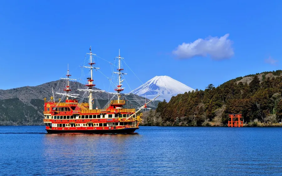 A sightseeing ship on Lake Ashi with the snow-capped cone of Mount Fuji behind it